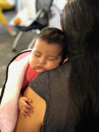 A baby sleeps on her mom's shoulder.